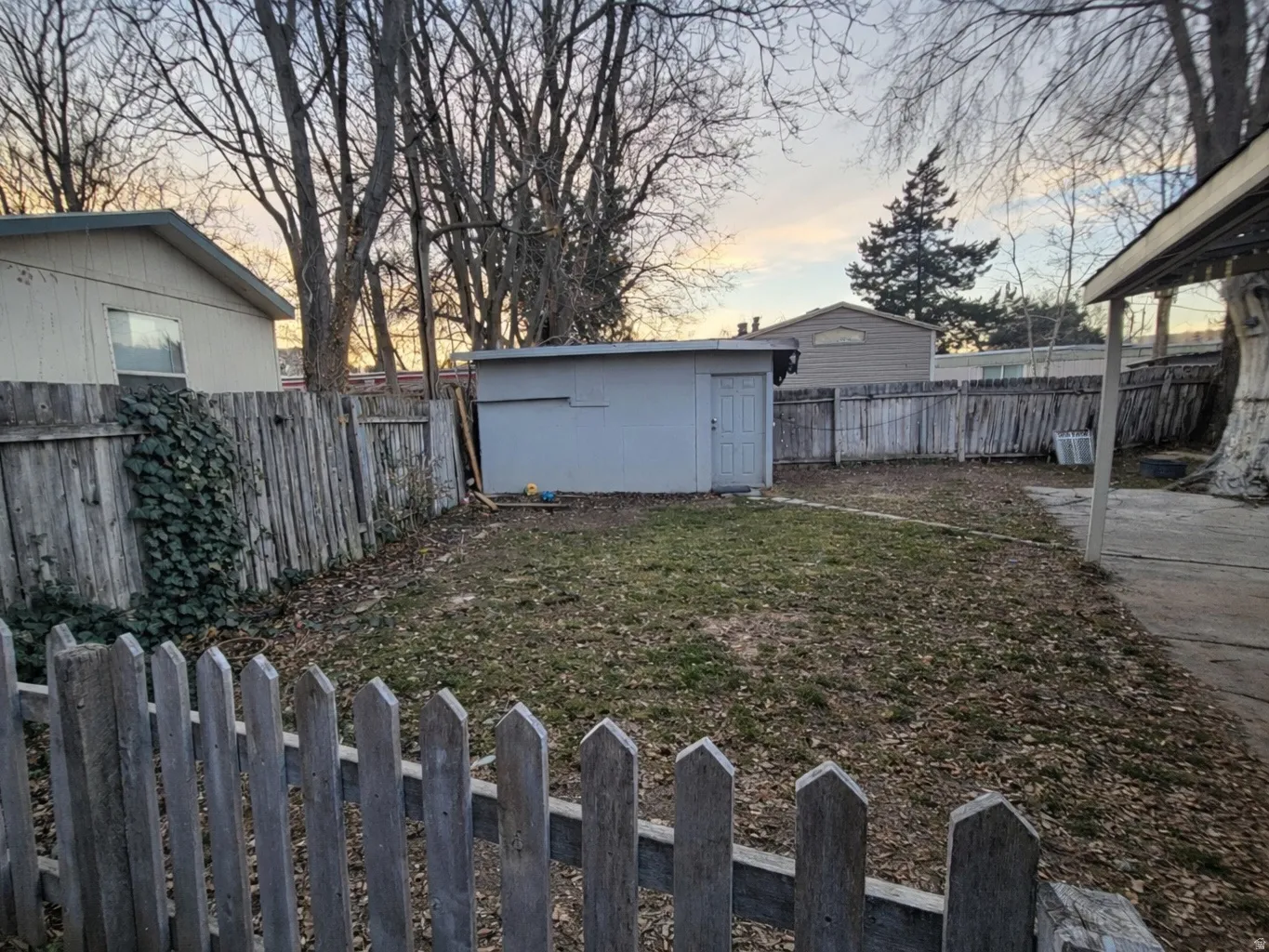 Yard at dusk with a fenced backyard and a storage shed