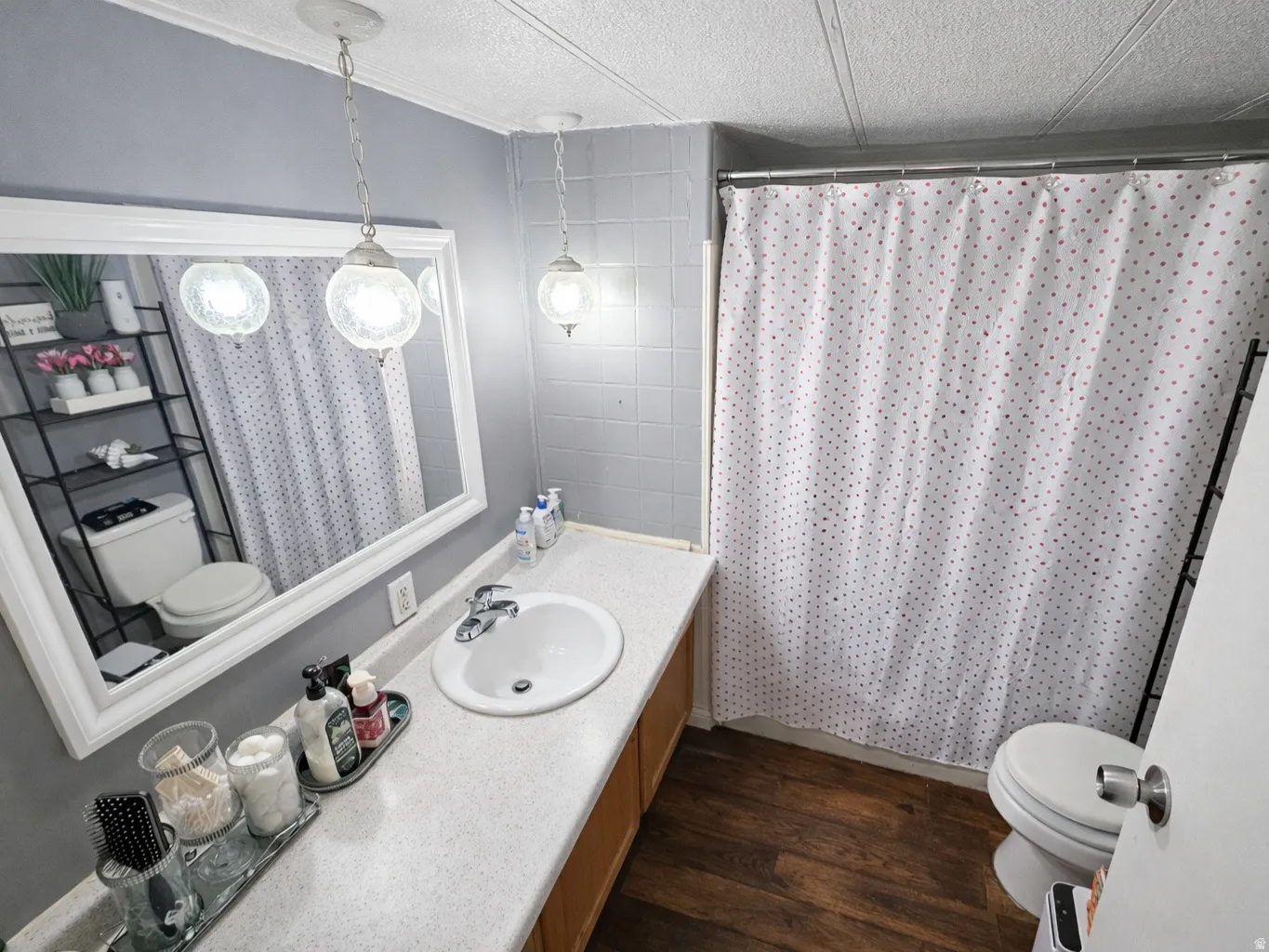 Full bath featuring vanity, a textured ceiling, and dark wood-type flooring