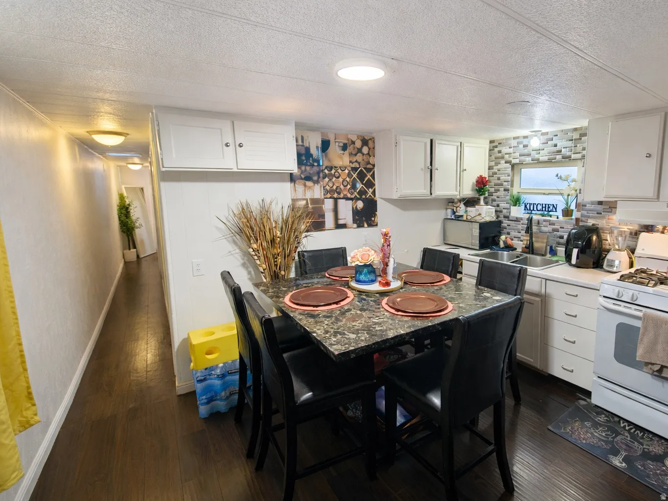 Dining space with a textured ceiling and dark wood-style floors