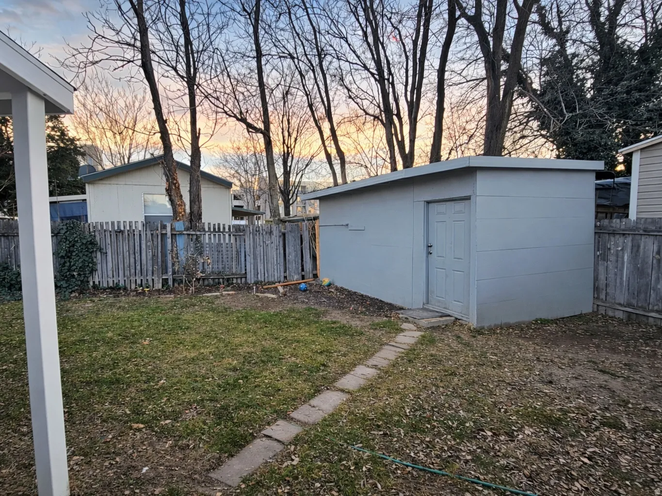 Yard at dusk with a fenced backyard and an outdoor structure