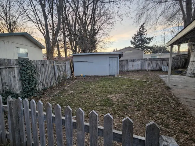 Yard at dusk with a fenced backyard and a storage shed