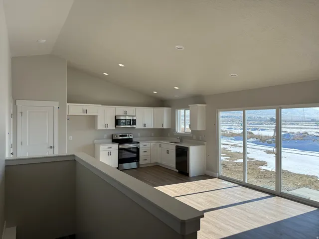 Kitchen featuring stainless steel appliances, white cabinets, recessed lighting, vaulted ceiling, and dark wood-type flooring