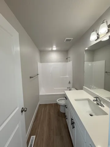 Full bath featuring  shower combination, dark wood-style floors, and vanity
