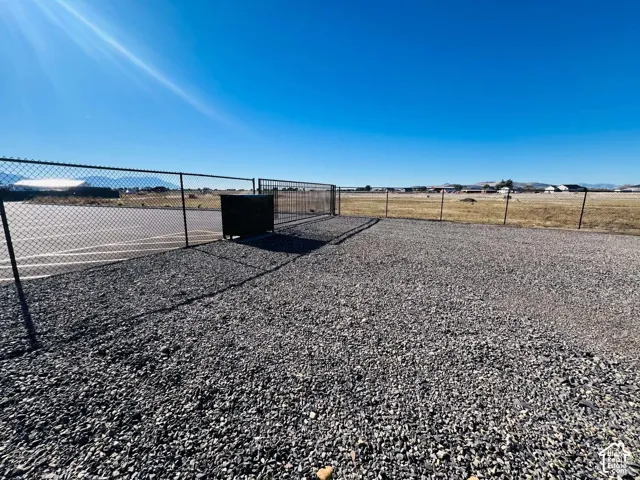 Fenced lot featuring gravel surfacing, paved parking area, and gated entry