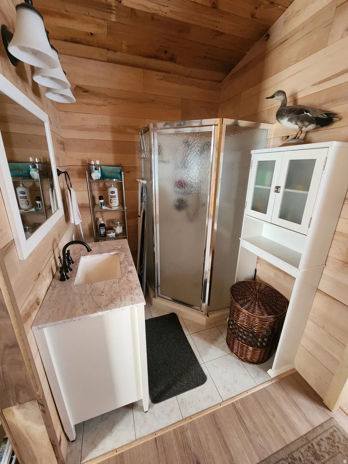 Bathroom featuring wood walls, a stall shower, vanity, a vaulted wooden ceiling, and light tile patterned floors
