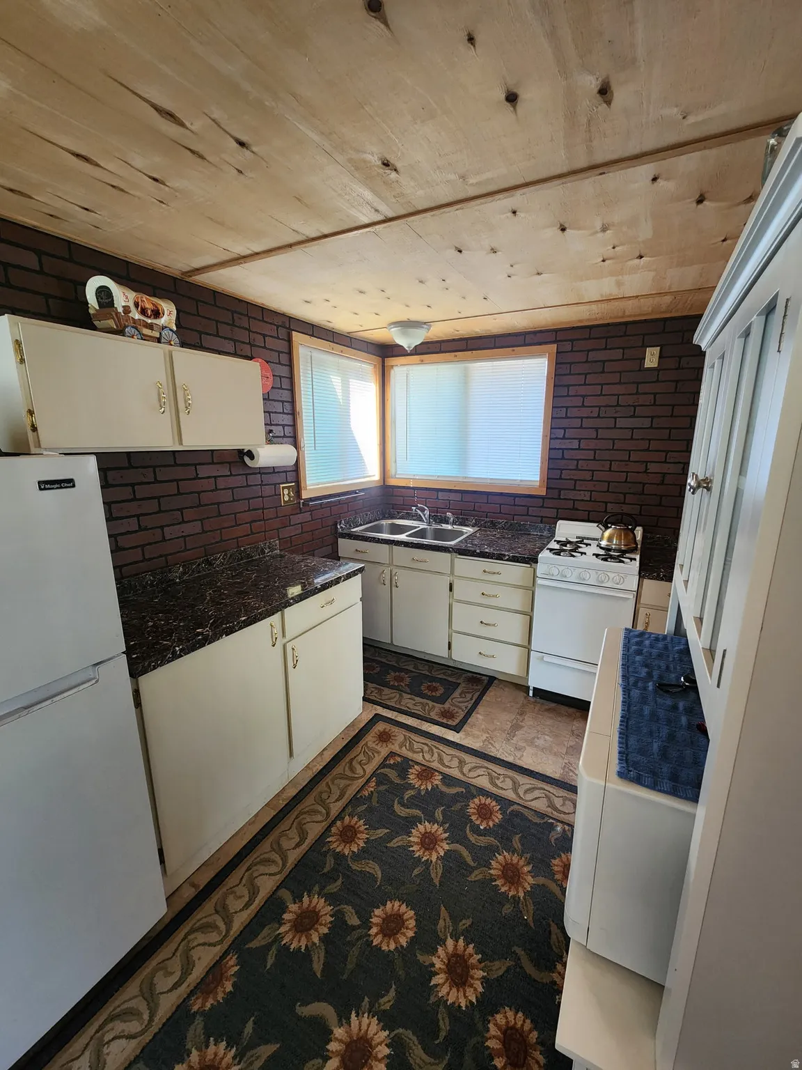 Kitchen featuring white appliances and white cabinets. Stove/Oven is Propane Gas