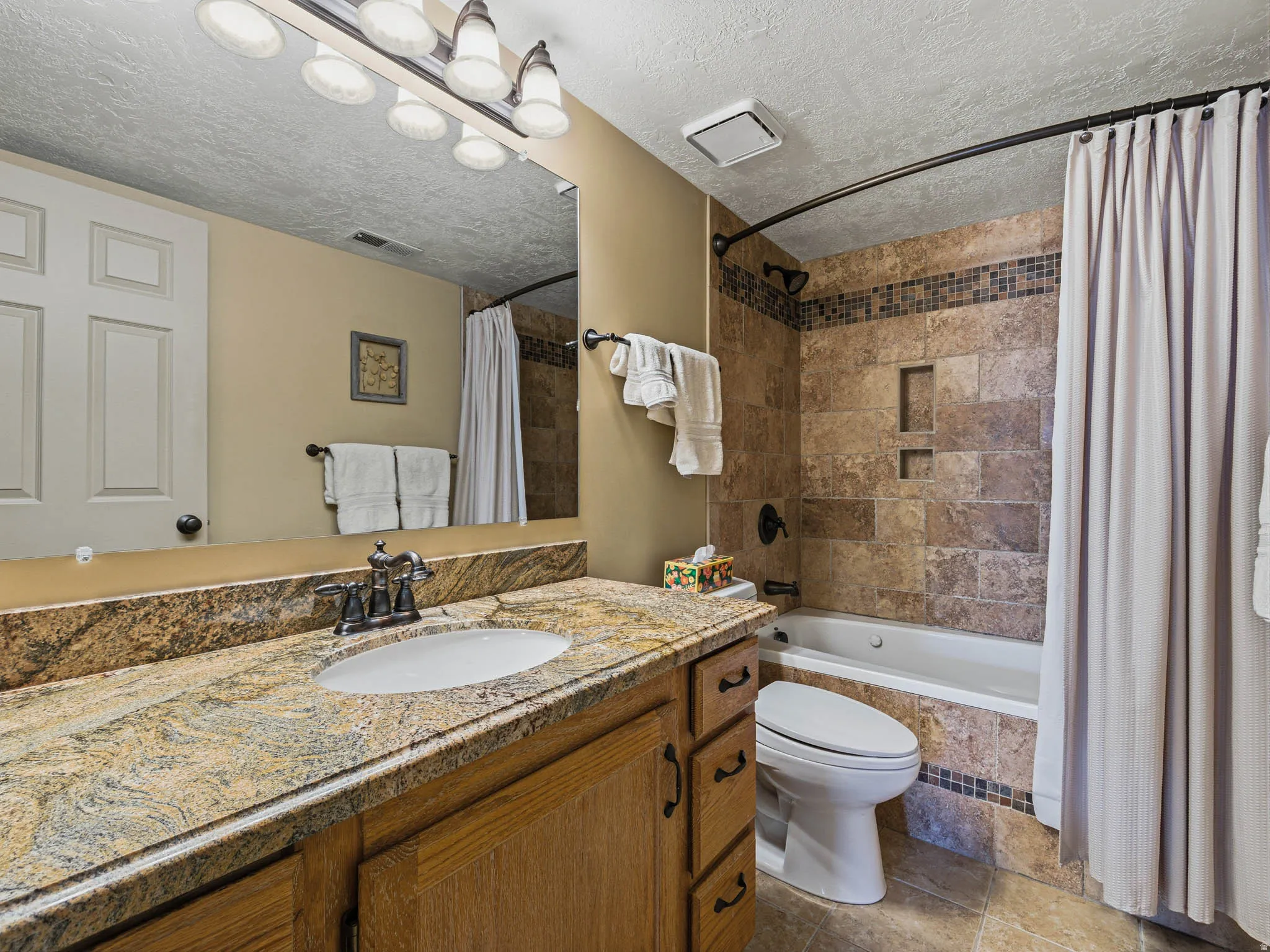 Bathroom with vanity, tiled shower / bath combo, and a textured ceiling