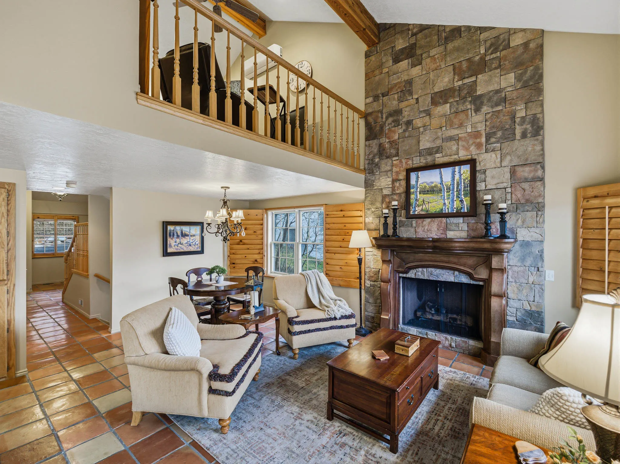 Living room featuring a fireplace, vaulted ceiling with beams, a chandelier, and log walls