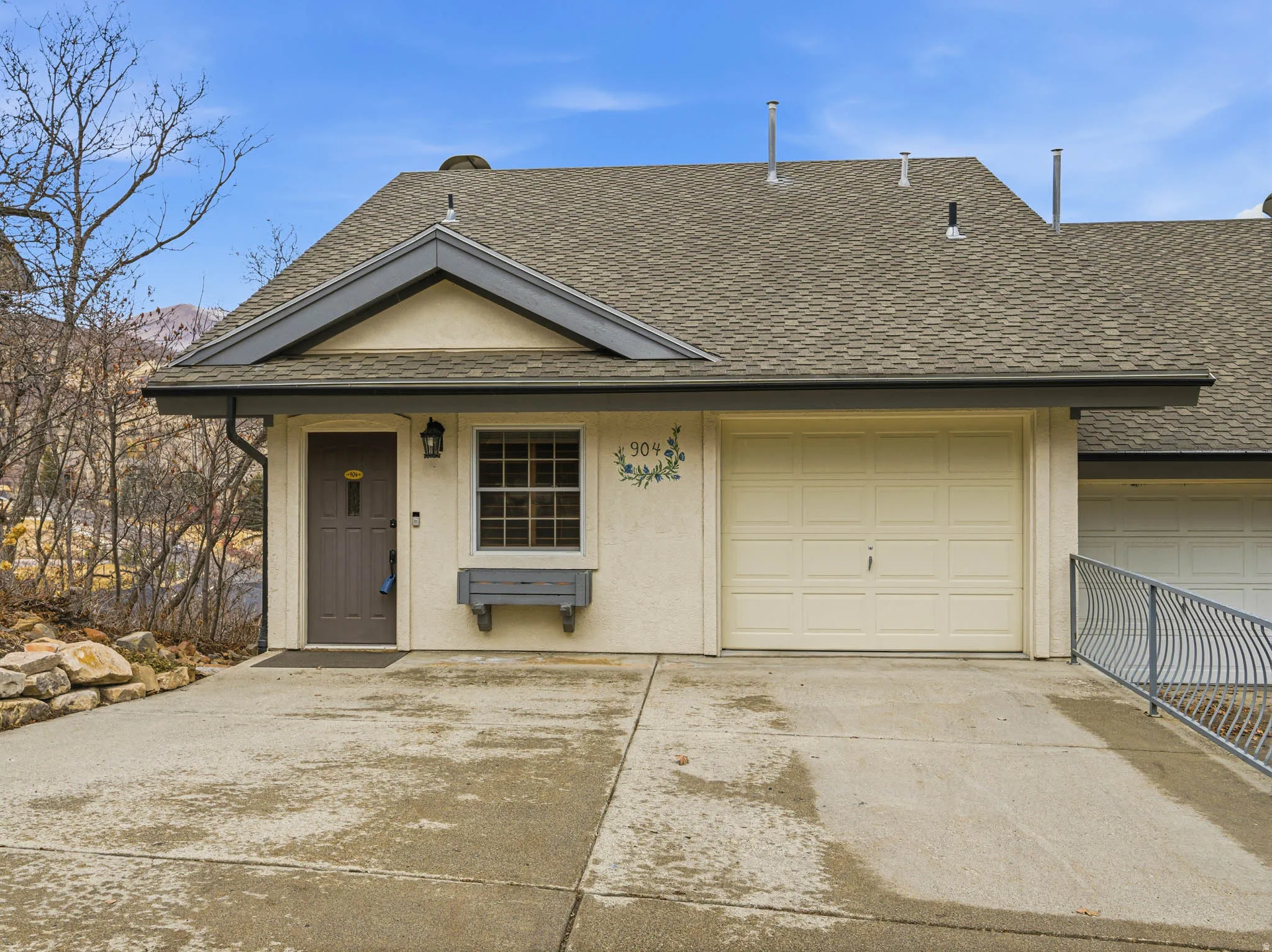 View of front of home with a shingled roof, driveway, and stucco siding