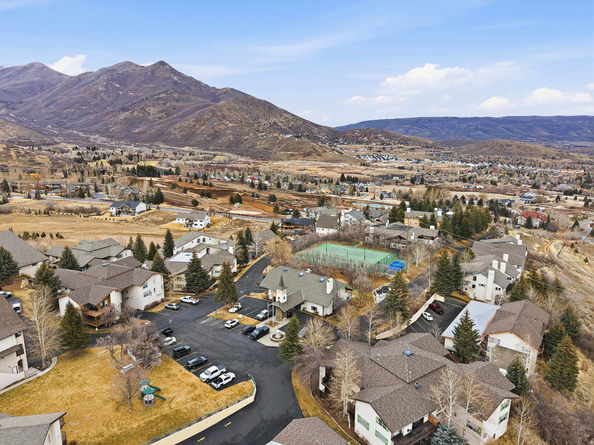 Aerial view of property and surrounding area featuring nearby suburban area and a mountainous background