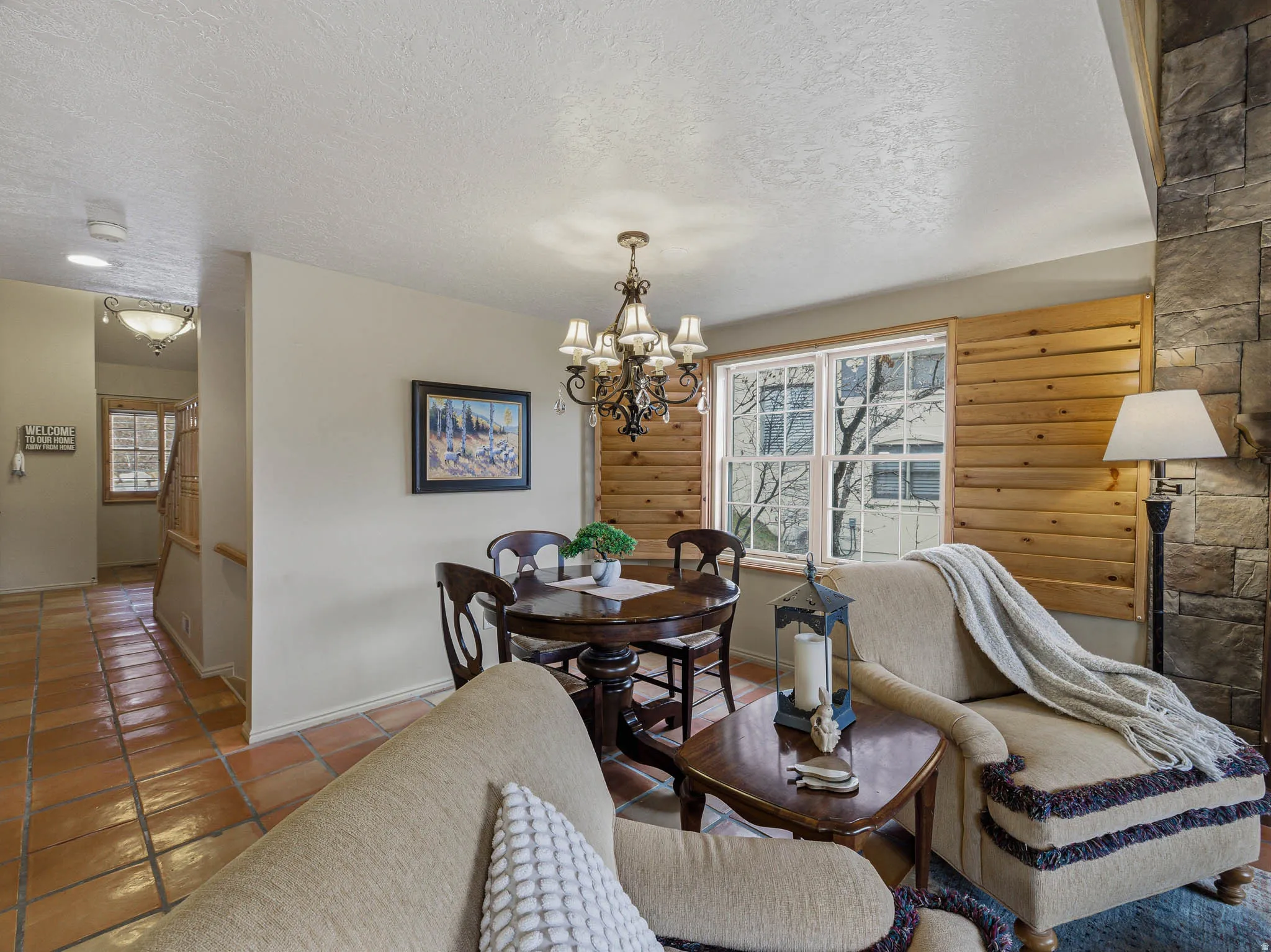 Tiled dining space featuring a textured ceiling, a chandelier, and log walls