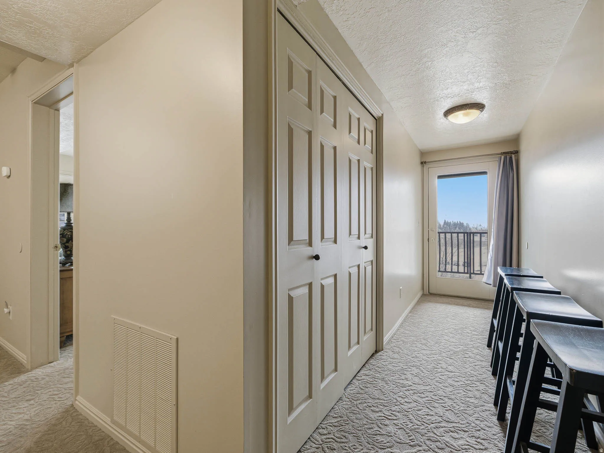Corridor with a textured ceiling and light carpet