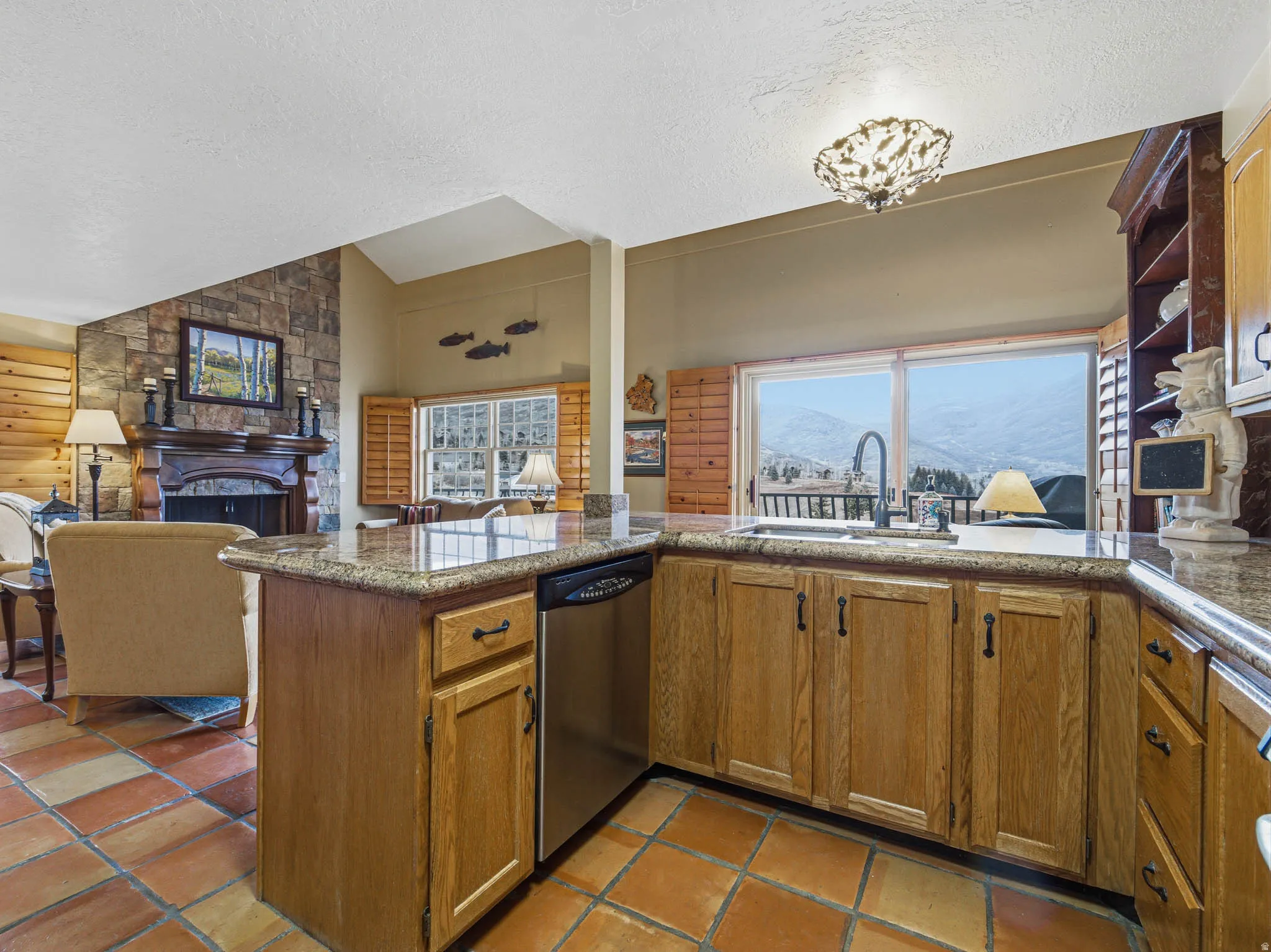 Kitchen with a fireplace, a peninsula, dishwasher, a mountain view, and healthy amount of natural light