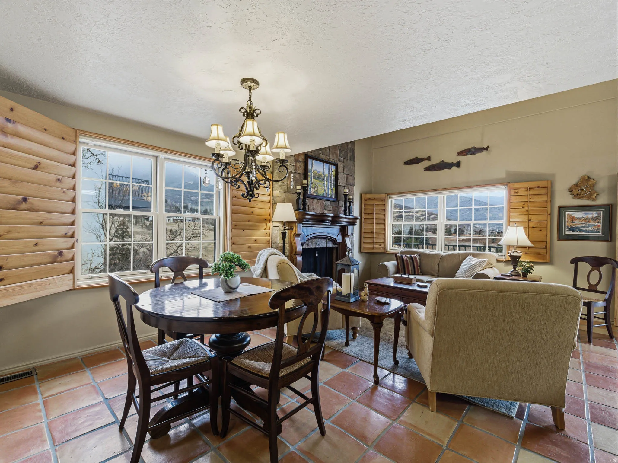 Dining room featuring a textured ceiling, hanging lights, a fireplace, and log walls