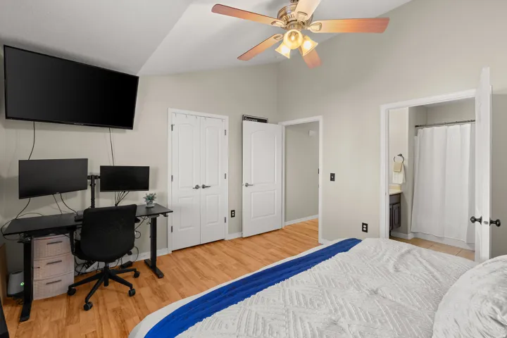 Bedroom with a desk, light wood finished floors, lofted ceiling, a closet, and a ceiling fan