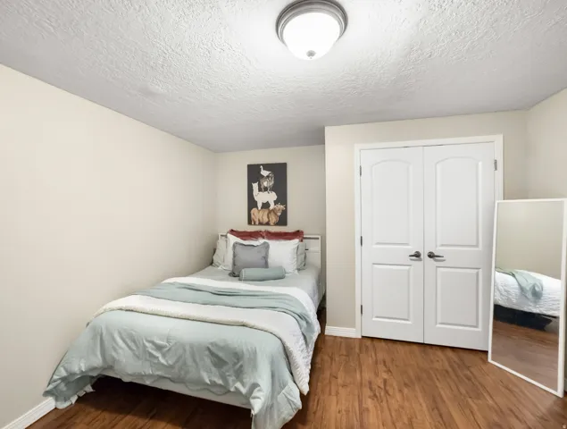 Bedroom with a textured ceiling, wood finished floors, and a closet