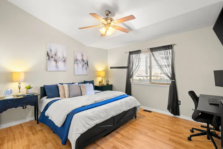 Bedroom featuring light wood-style floors, an office area, vaulted ceiling, and ceiling fan
