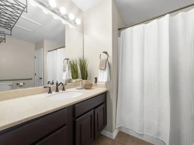 Full bathroom featuring vanity, dark tile patterned flooring, and shower / bath combination with curtain