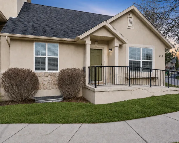 Stucco exterior with stone accent, covered entry, and black metal railing