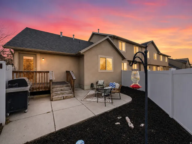 Private outdoor patio featuring a concrete slab, a wooden deck with stairs, and a white vinyl fence