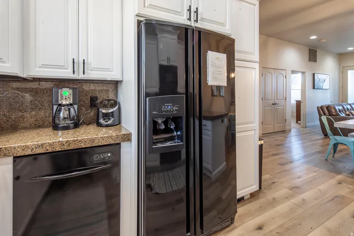 Kitchen with black appliances, light wood-style flooring, white cabinetry, recessed lighting, and tile countertops