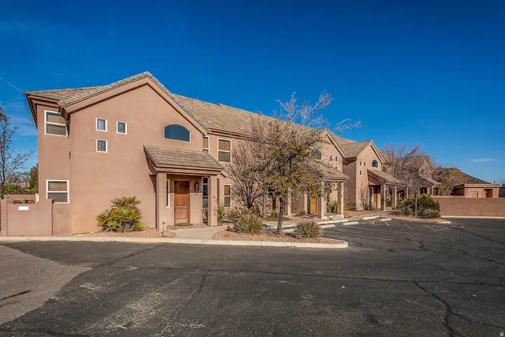 View of front of property with stucco siding, a tile roof, and uncovered parking