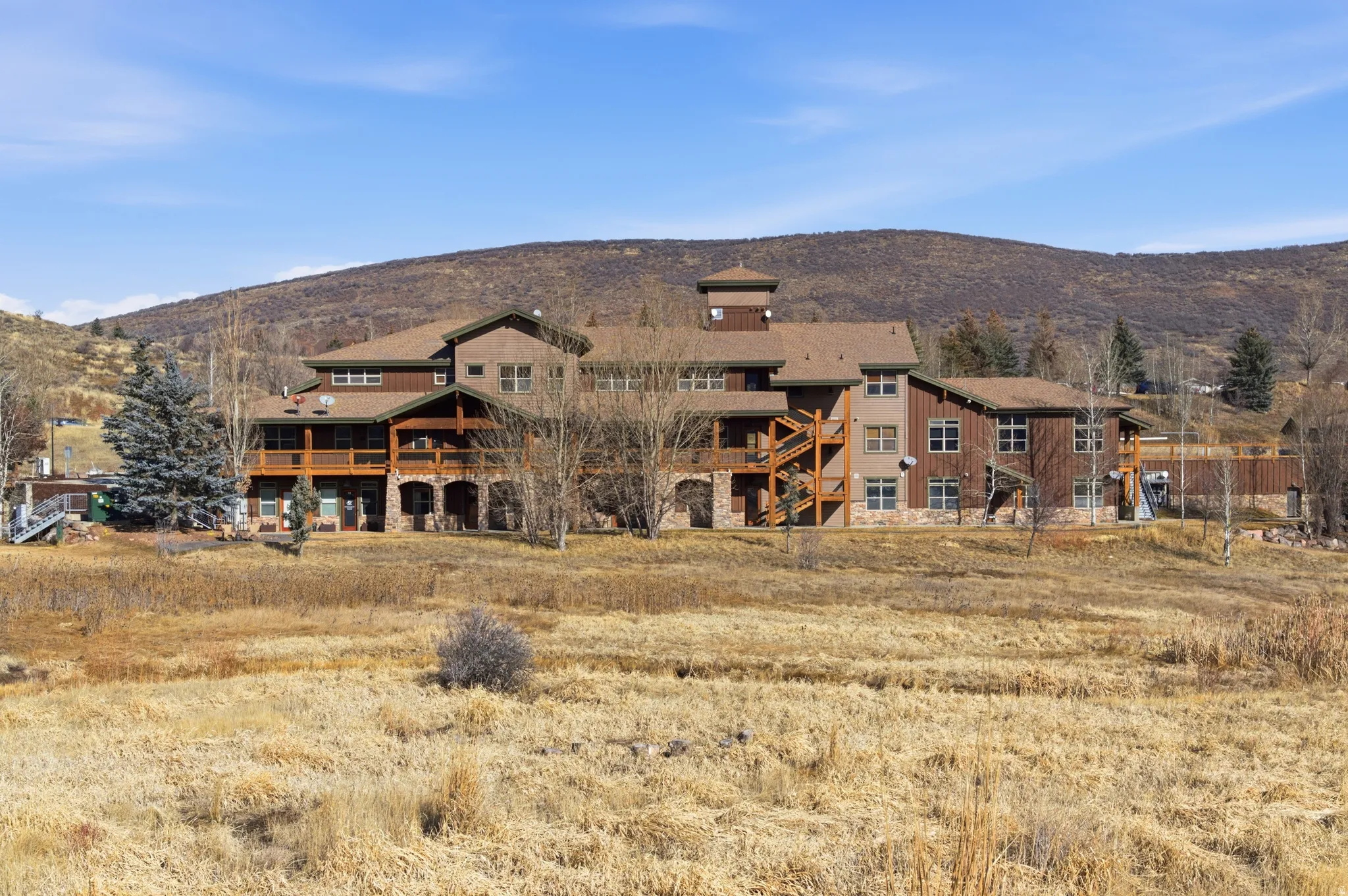 Rear view of house featuring a mountain view, a balcony, and stone siding