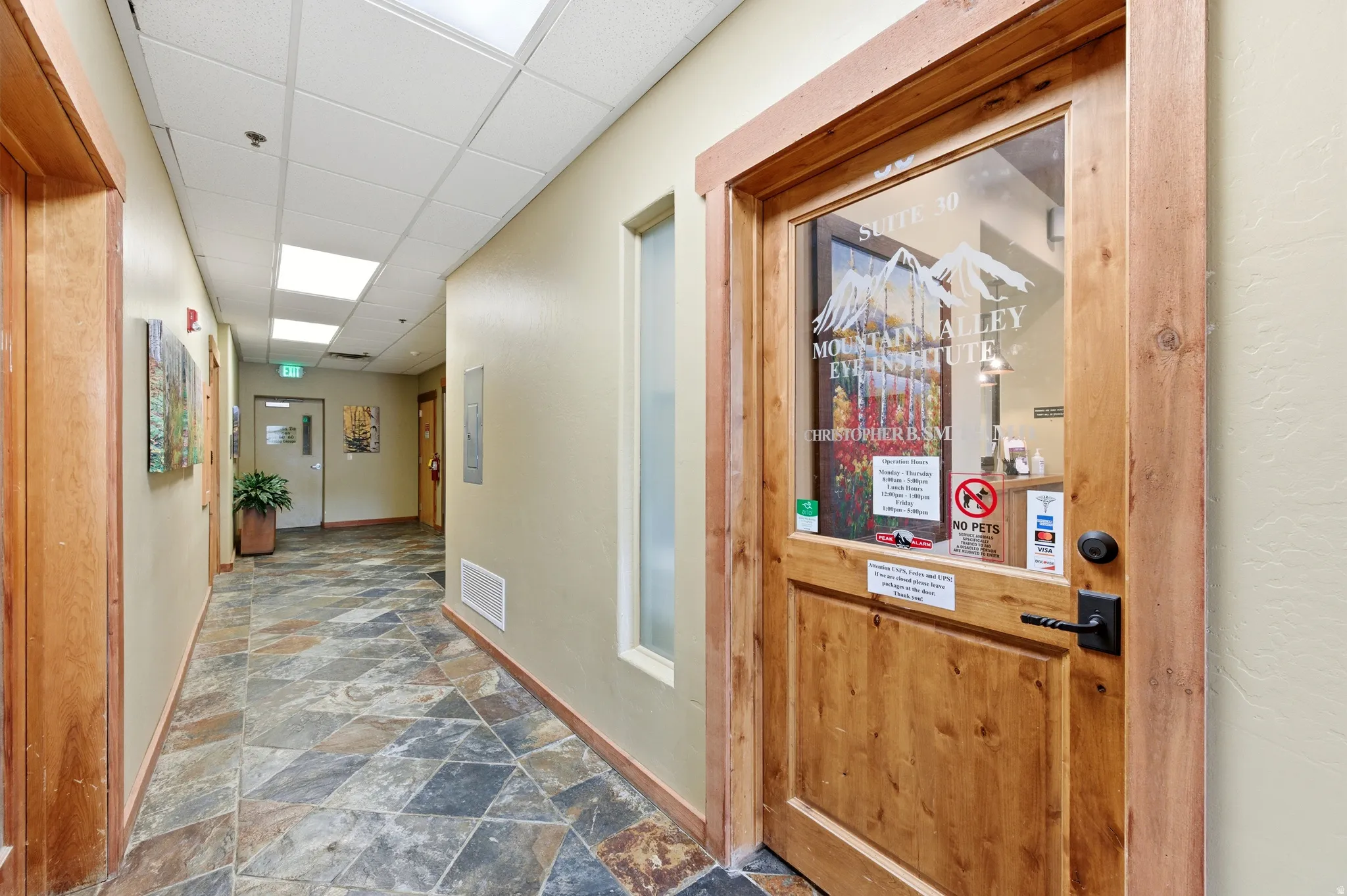 Hall featuring a drop ceiling and dark stone finish flooring