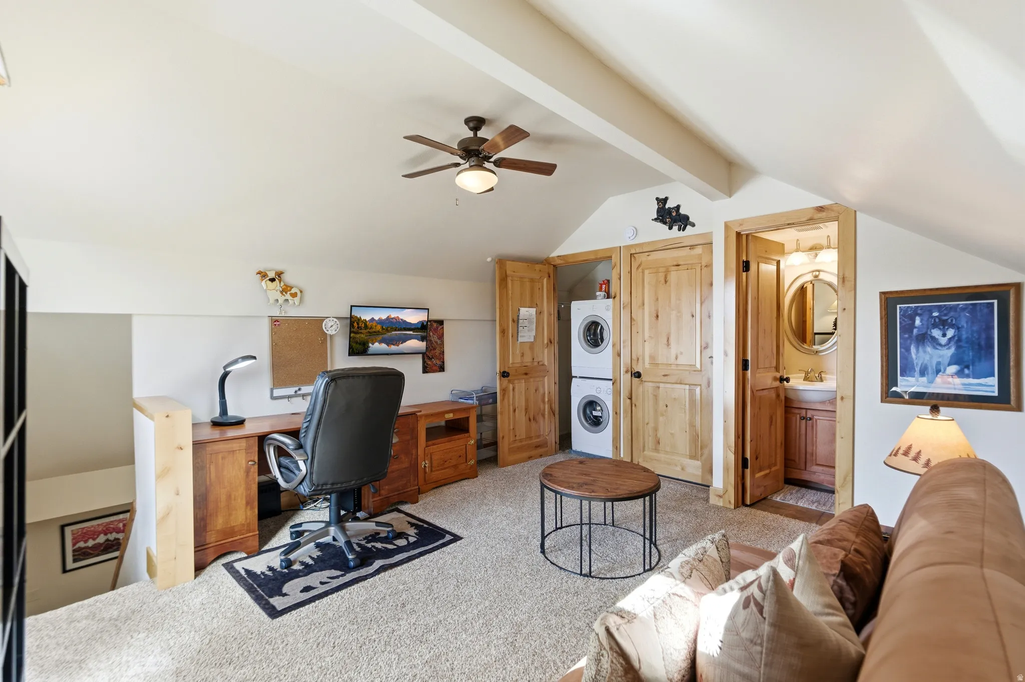 Office area with stacked washer / drying machine, light colored carpet, a ceiling fan, and beamed ceiling