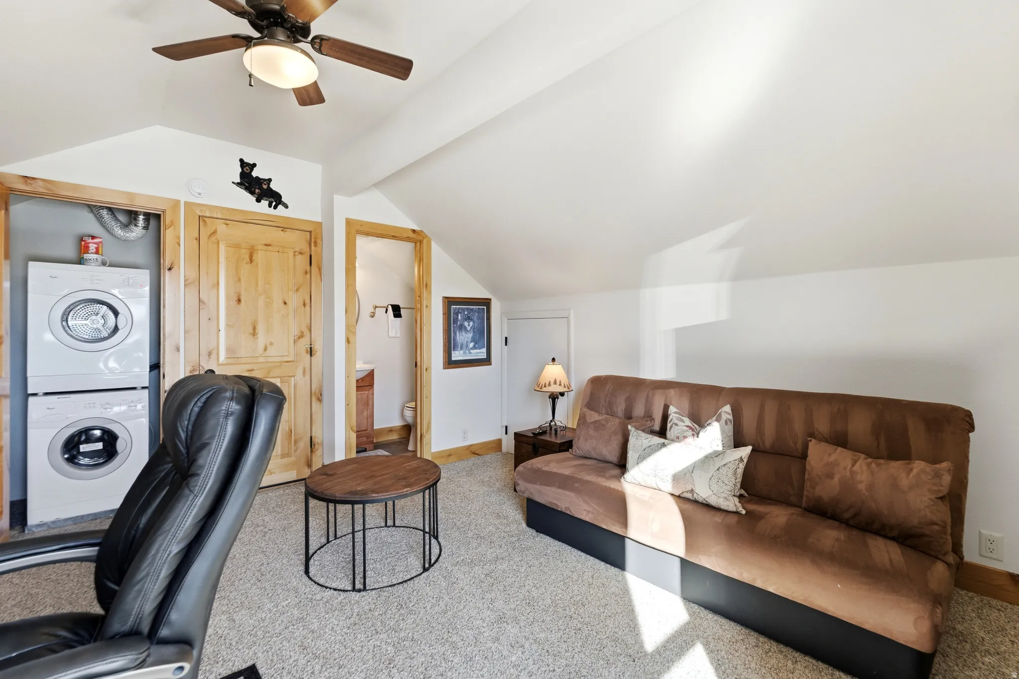 Office space with lofted ceiling, carpet flooring, stacked washer / dryer, and ceiling fan