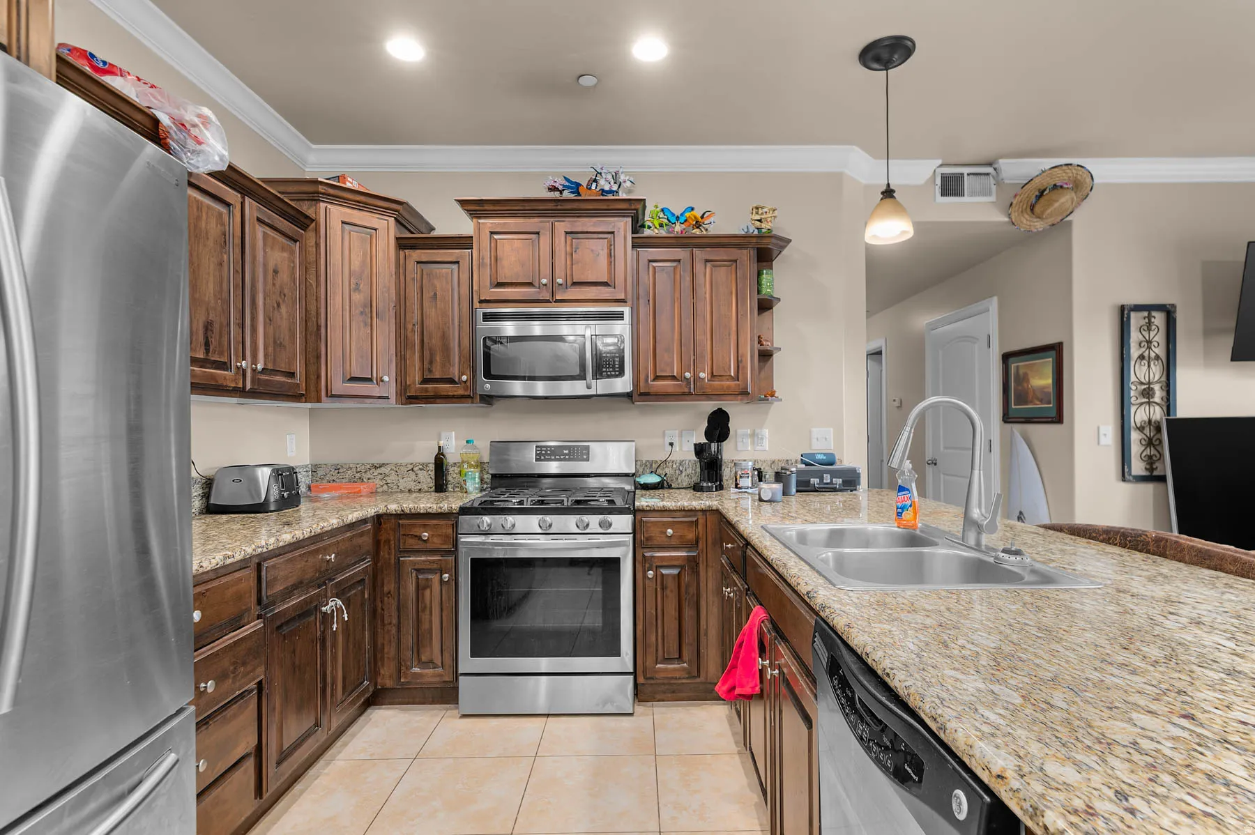 Kitchen with stainless steel appliances, open shelves, crown molding, decorative light fixtures, and a peninsula