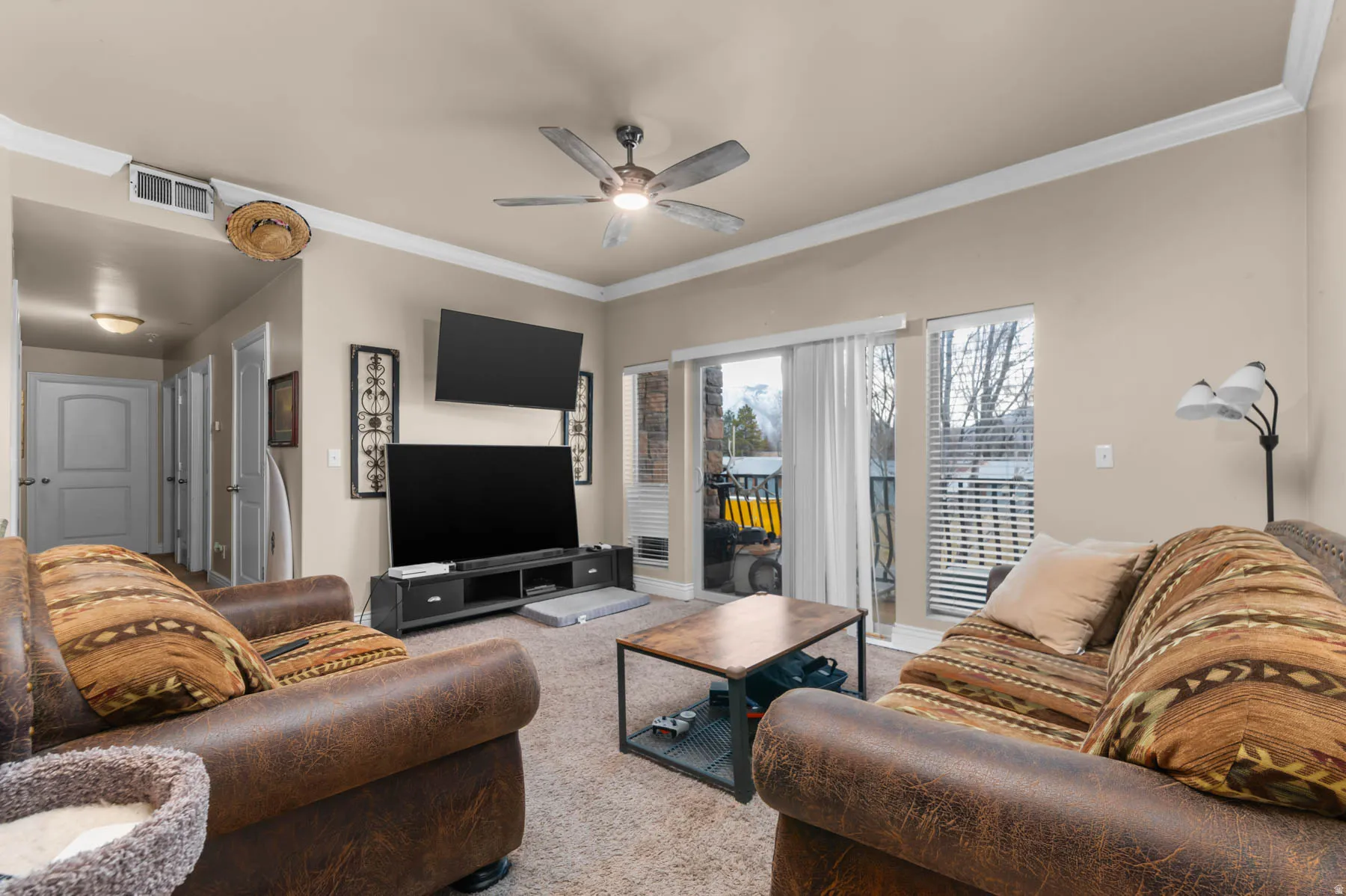 Living room with crown molding, ceiling fan, and carpet flooring