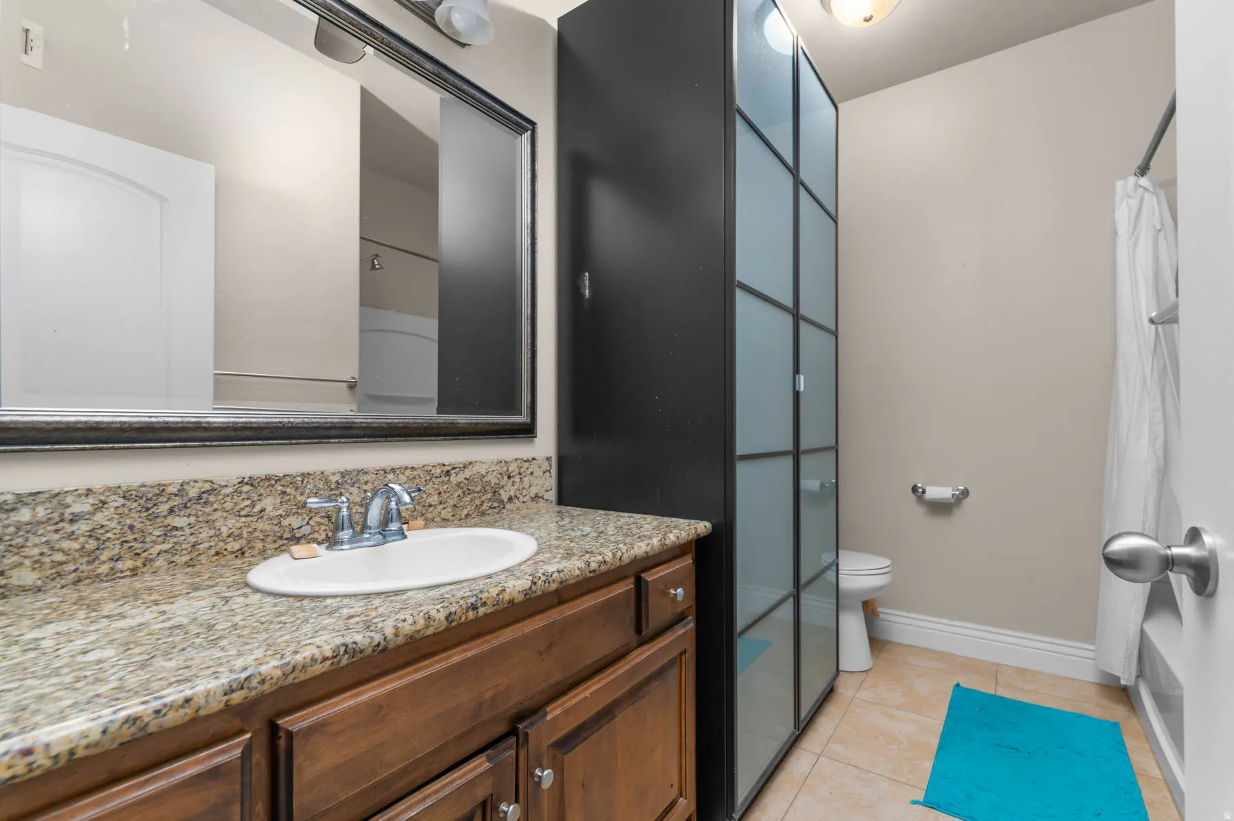 Bathroom with vanity, light tile patterned floors, and shower / bathtub combination with curtain