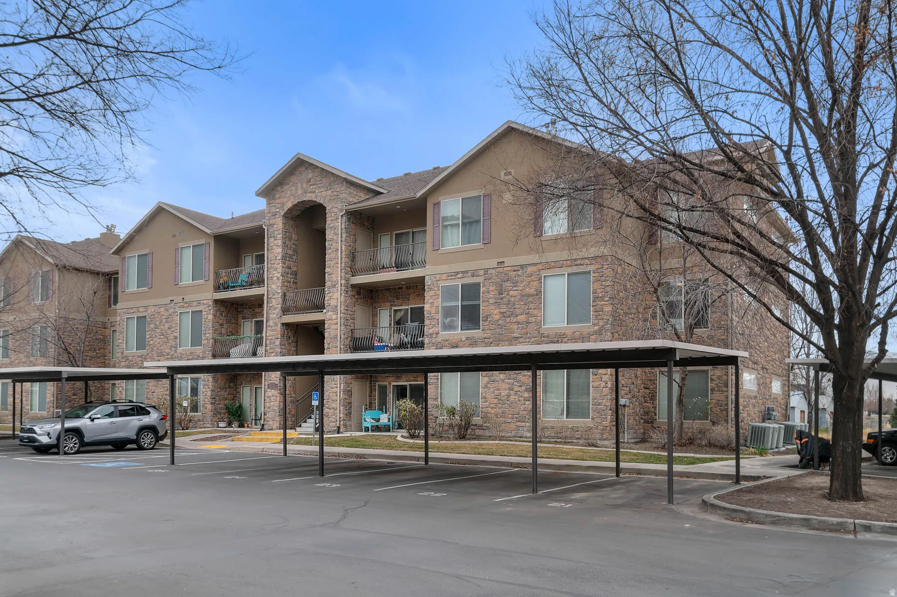 View of apartment building / complex featuring covered parking