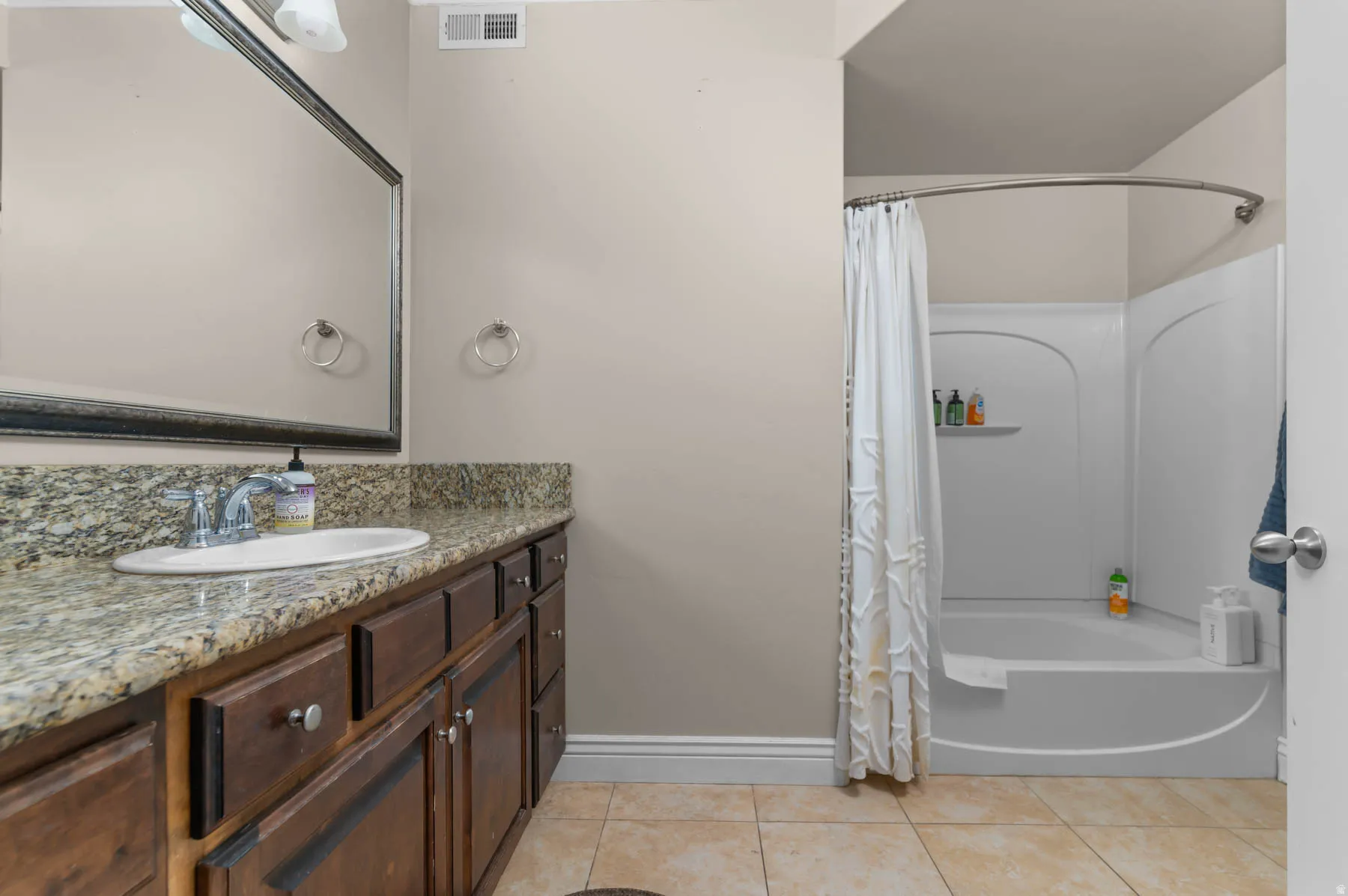 Bathroom with shower / bath combination with curtain, vanity, and light tile patterned floors
