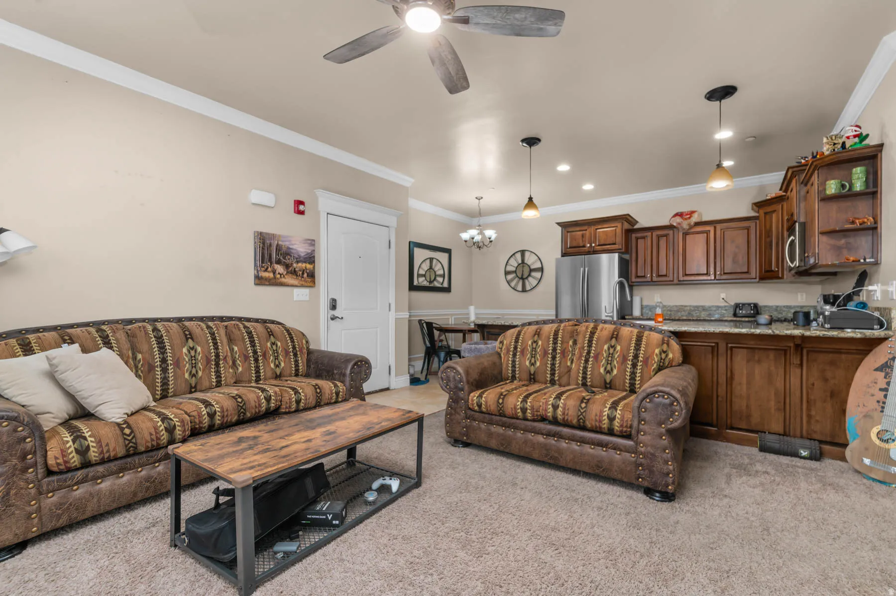 Living room featuring crown molding, ceiling fan, hanging lights, and light carpet