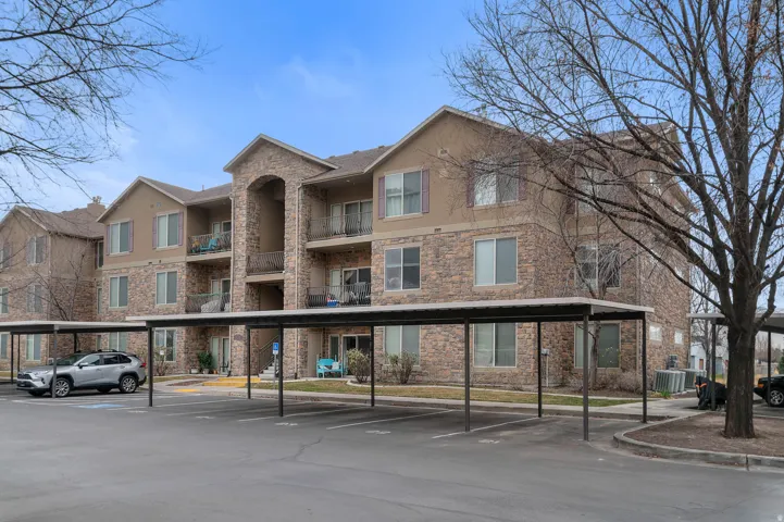 View of apartment building / complex featuring covered parking