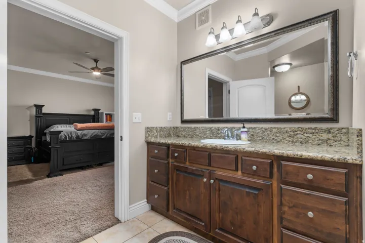 Bathroom with light colored carpet, crown molding, vanity, light tile patterned flooring, and a ceiling fan