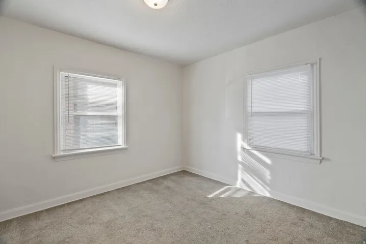 Unfurnished room featuring light carpet and baseboards