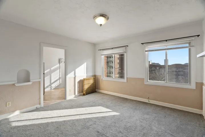 Carpeted spare room featuring radiator, a textured wall, and a textured ceiling