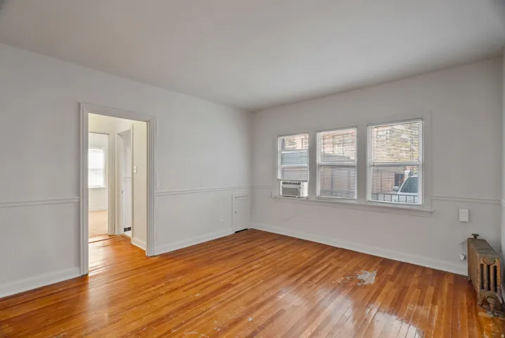 Spare room with light wood-type flooring, plenty of natural light, radiator heating unit, and cooling unit
