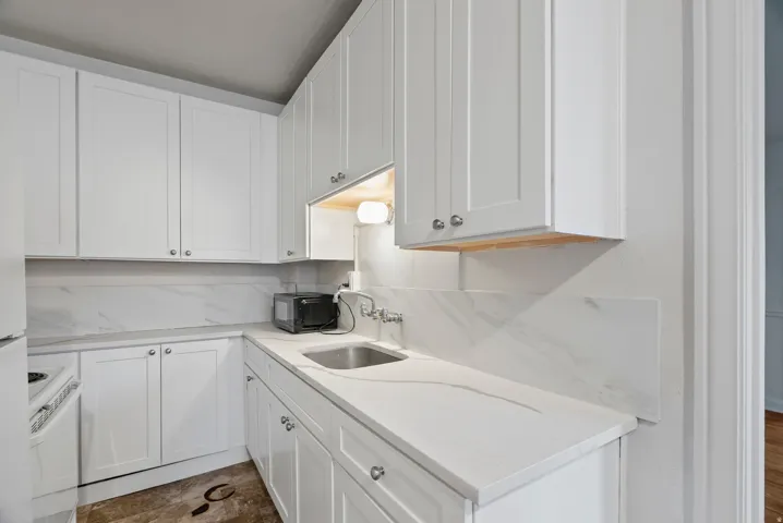 Kitchen with white cabinets, white electric range, light stone counters, and tasteful backsplash