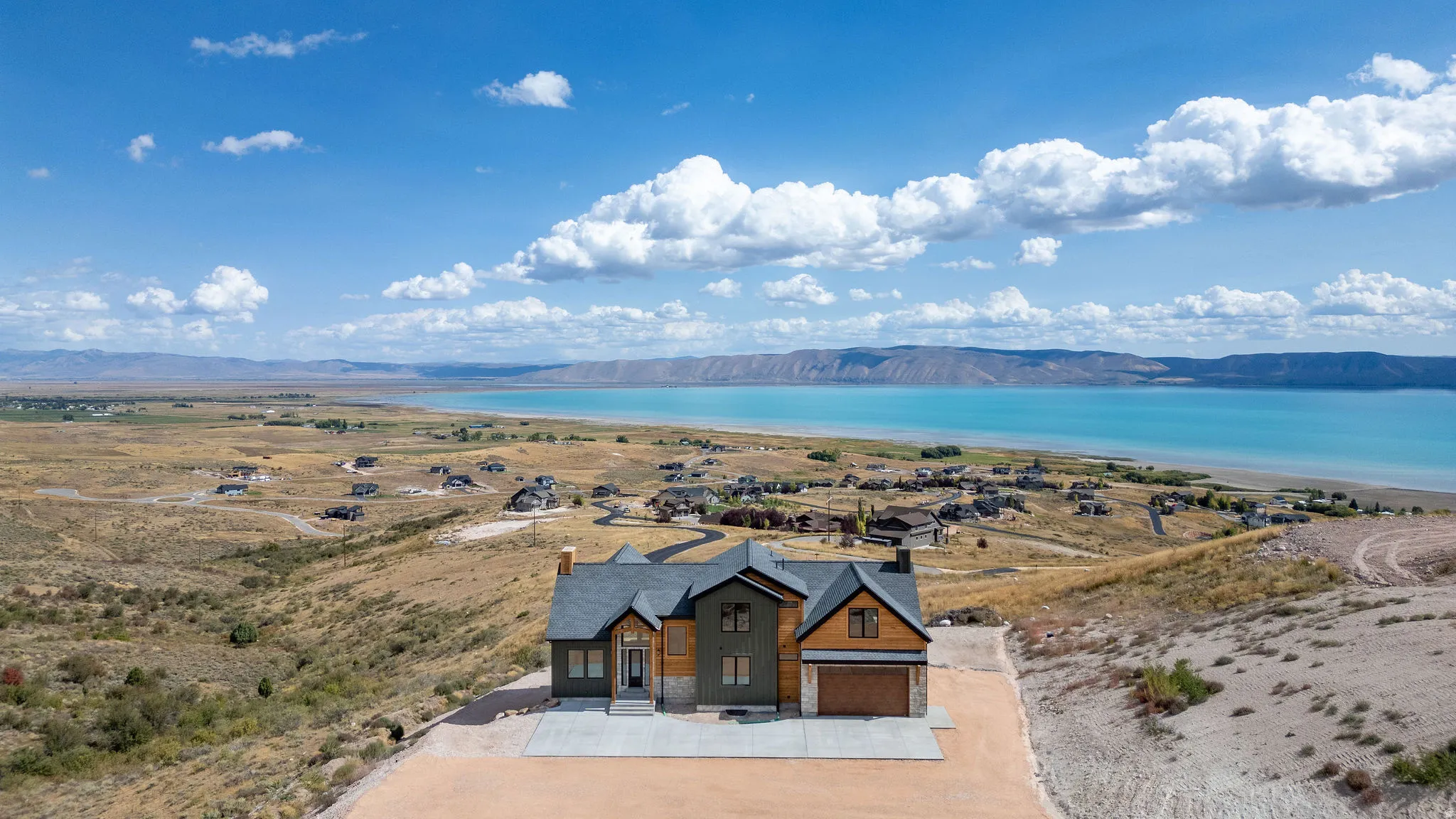 View of front of house featuring stone siding, a water and mountain view, concrete driveway, and a garage