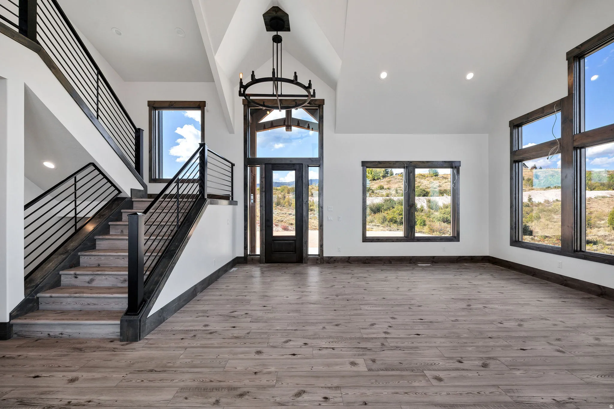 Entrance foyer with french doors, light wood-style flooring, vaulted ceiling, a chandelier, and plenty of natural light