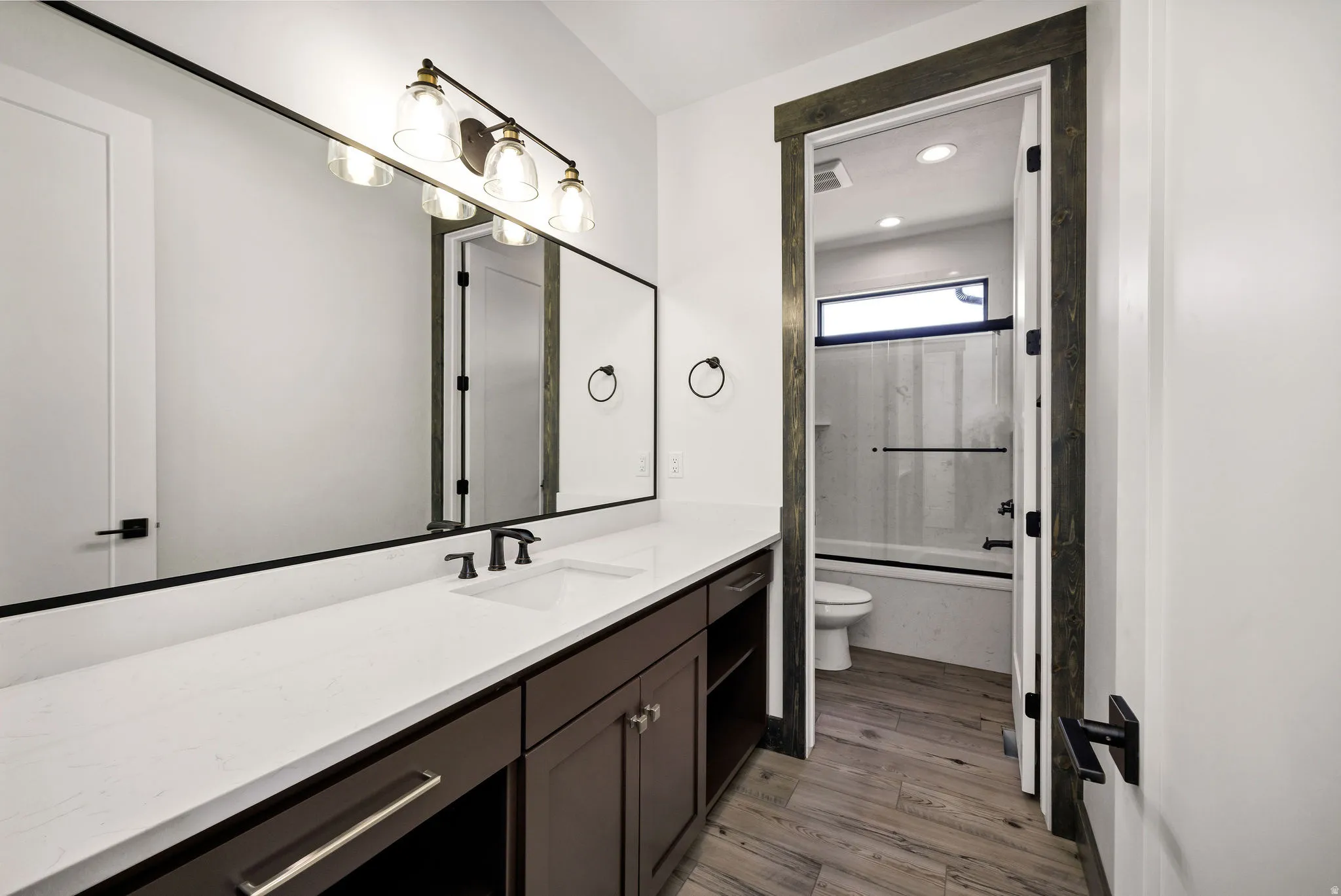 Full bathroom with vanity, combined bath / shower with glass door, light wood finished floors, and recessed lighting