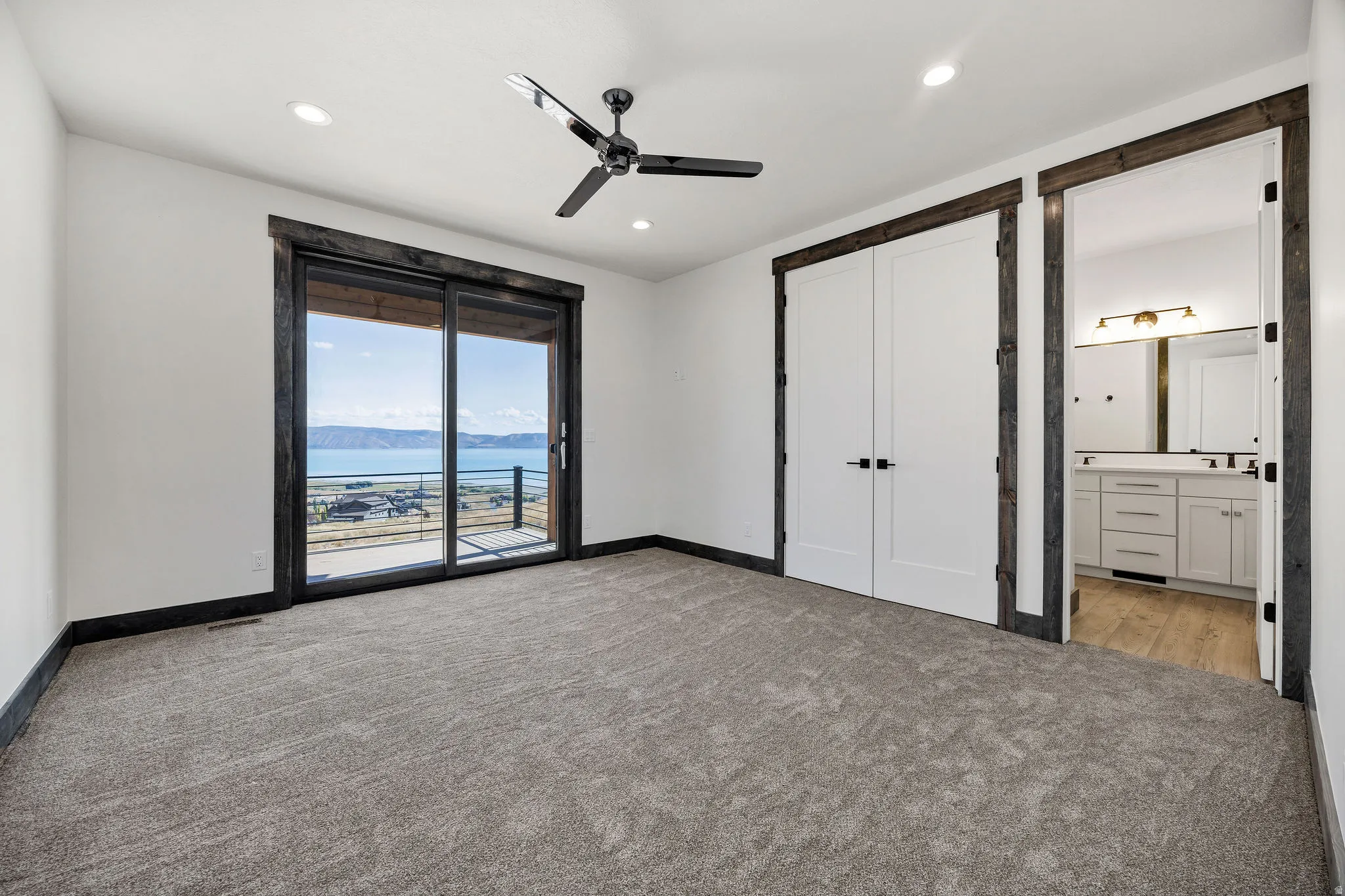 Unfurnished bedroom featuring a water and mountain view, access to outside, light carpet, ceiling fan, and recessed lighting