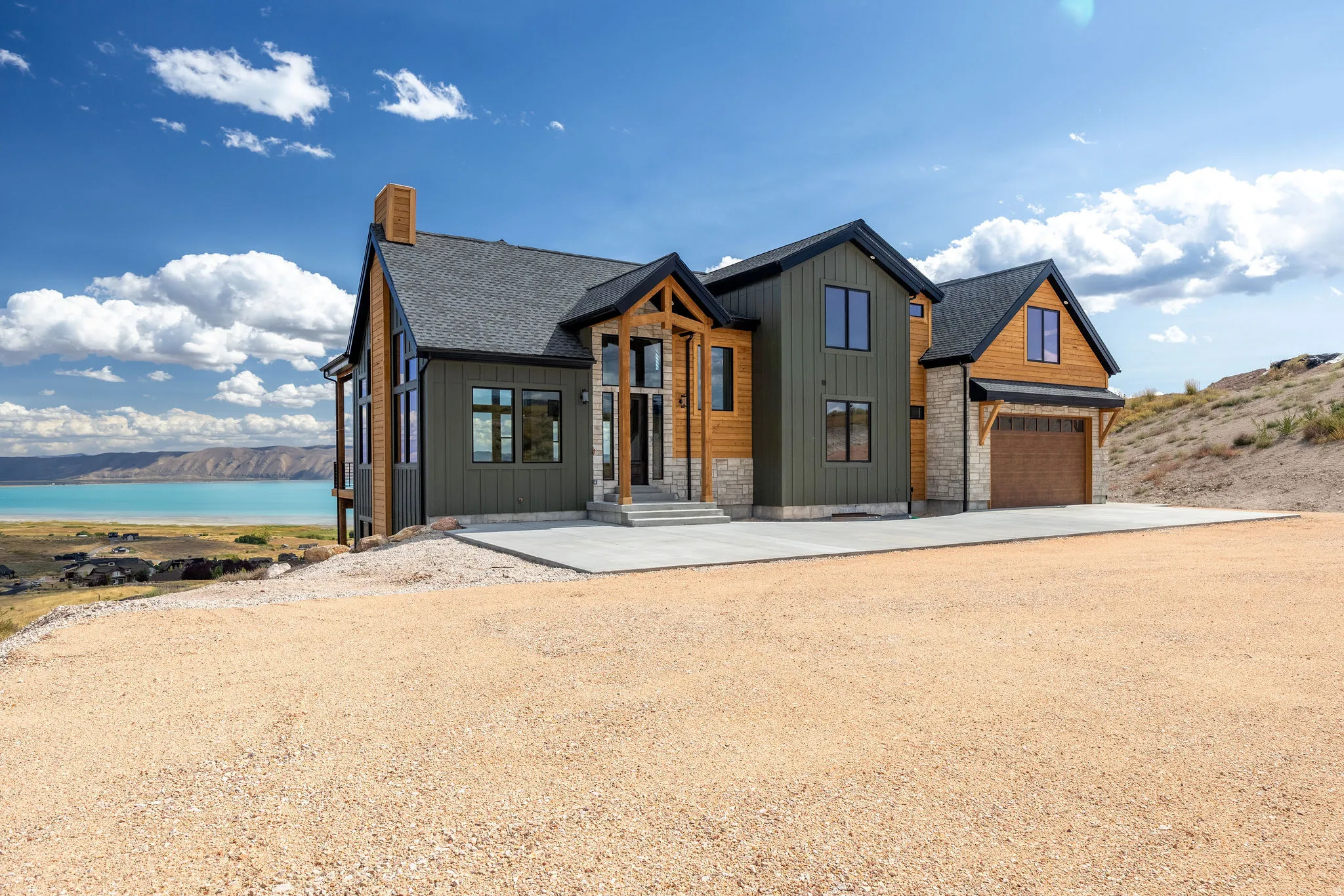 View of front of property with board and batten siding, driveway, stone siding, and a chimney