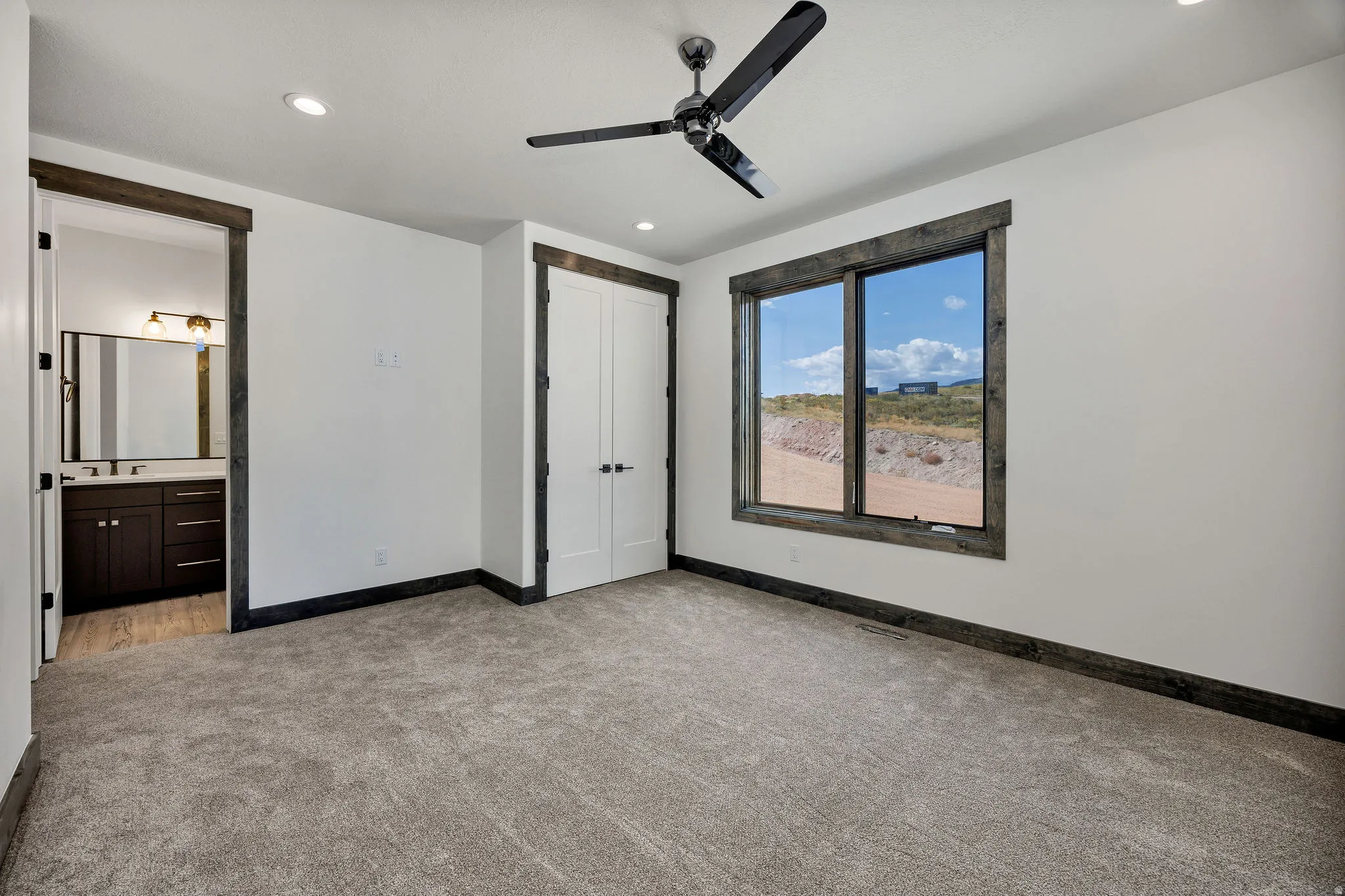 Unfurnished bedroom featuring light carpet, a ceiling fan, a closet, recessed lighting, and ensuite bathroom