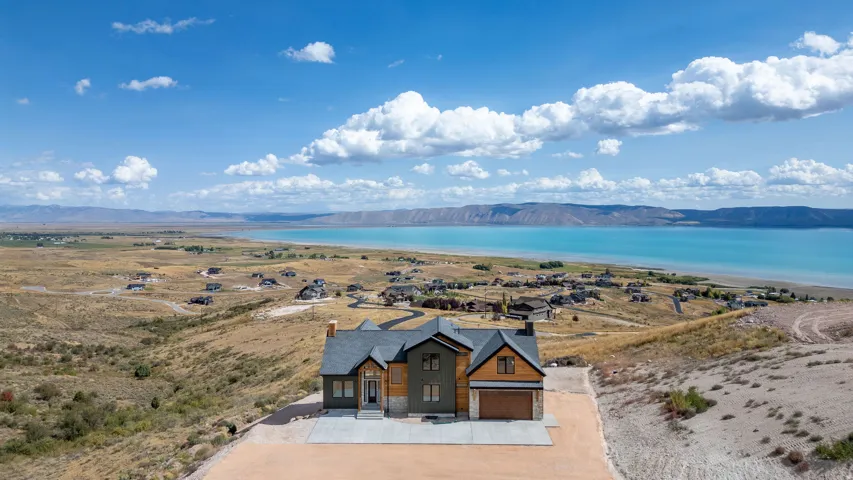 View of front of house featuring stone siding, a water and mountain view, concrete driveway, and a garage