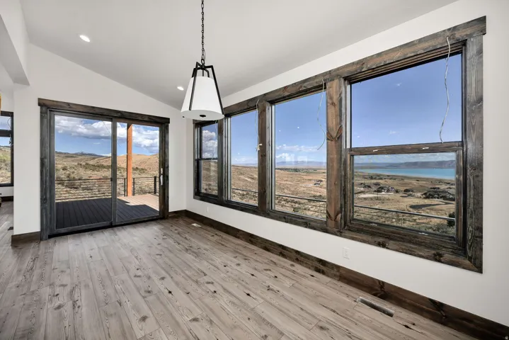 Unfurnished dining area with lofted ceiling, light wood-style flooring, a mountain view, and recessed lighting